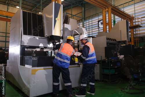 Foto Workers examine machinery inside a manufacturing facility during the daytime whi
