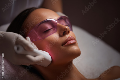 Hair removal clinic treatment for woman with laser goggles and aesthetician in a clinic