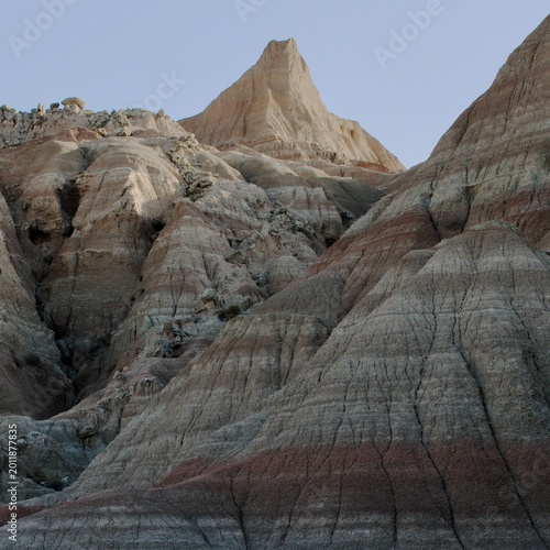 A sunlit peak rises among shadowed, layered rocks in the Badlands 