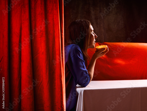 Scene of a woman in an interior behind a velvet curtain