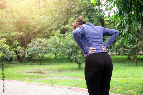 Принти на полотні Back view of woman feeling tired and holding lower back after outdoor workout session in park