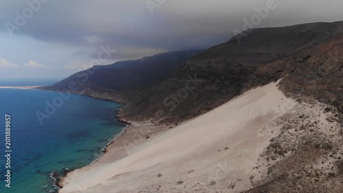 Aerial flight over a red rock formation on the coast of socotra island by the blue ocean, perfect for exotic travel documentaries, nature exploration videos or alien landscape backgrounds