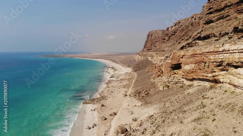 Aerial flight over turquoise ocean and steep rocky cliffs on the coast of socotra island yemen, ideal for exotic travel documentaries, nature exploration videos or tourism marketing backgrounds