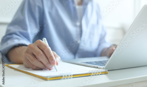 close up on businessman hand using pen to writing schedule on calendar to make appointment meeting or manage timetable each day at house for work from home concept