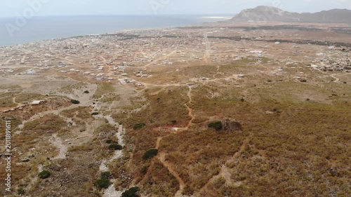 Expansive aerial video from a very distant viewpoint of Socotra Island's landscape, featuring vast wilderness, a distant coastline, and scattered human settlements
