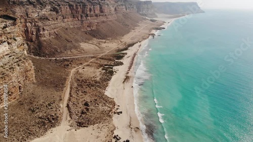 Panoramic aerial video of Socotra Island's rugged coastline, where desert cliffs meet the turquoise ocean, perfect for travel and adventure footage