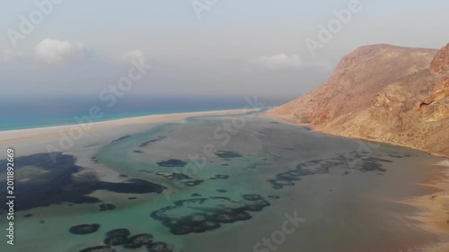 Panoramic aerial video showcasing the stunning coastline of Socotra Island, featuring a turquoise lagoon, pristine beach, and dramatic mountains
