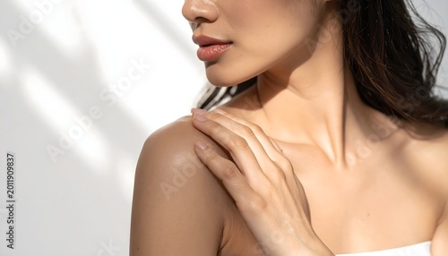 Primer plano de mujer con hombro descubierto y mano sobre la piel en composición de belleza minimalista