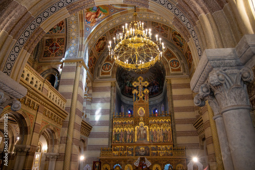 Photos Ornate interior of an Orthodox church with a golden iconostasis and grand chandelier under stone arches
