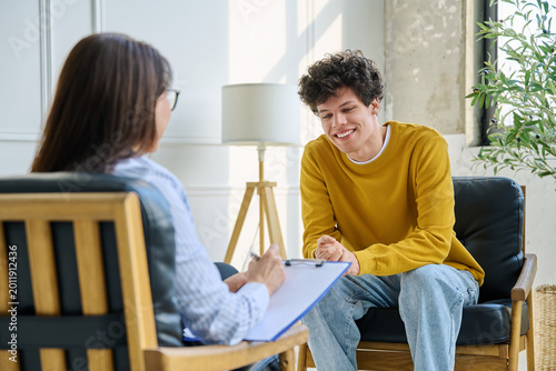 Happy teenage boy smiling during successful consultation with female psychologist