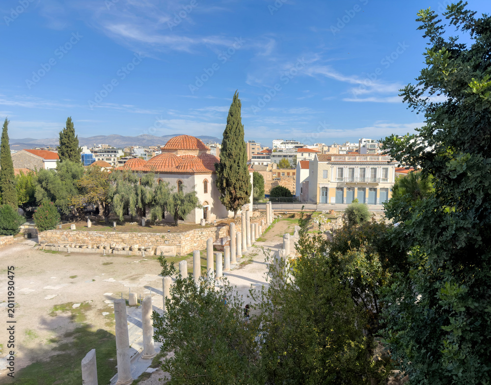 Fototapeta premium Ancient Agora in Athens, Greece, elevated view. Marble columns, archaeological ruins and a Byzantine church, blue sky