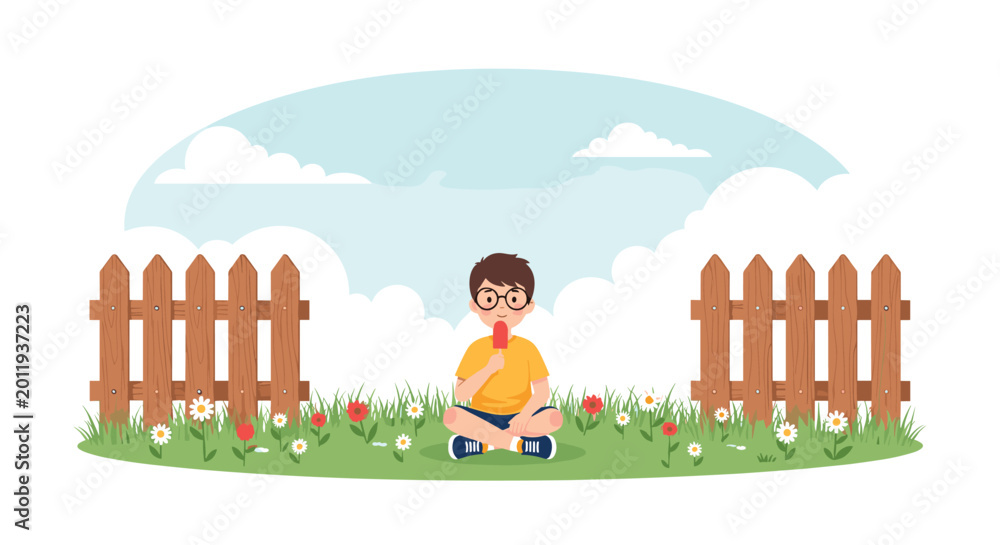 Fototapeta premium Boy with glasses sitting on the grass and enjoying a red popsicle in a beautiful field with flowers and a wooden fence.