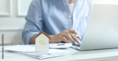close up on home model with percent sign and young man hand press on calculator to check and summary expense of home loan mortgage for refinance plan , people lifestyle concept