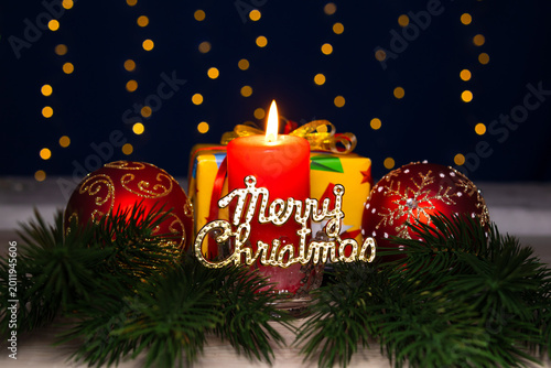 Between two large balls there is a burning candle with letters and a gift