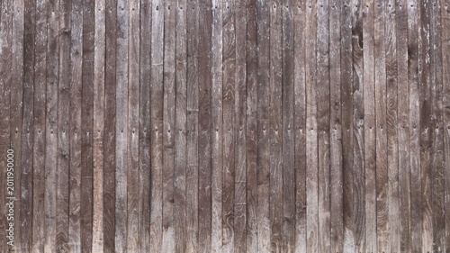 Beautiful old textured rustic fence made of narrow wooden planks with nail heads in the joint structure, gray plank solid fence made of natural aged wood as a country style background texture