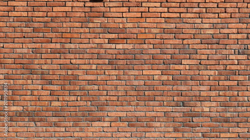 A detail of a red textured brick wall, rendered in bright sunlight, with old, weathered brickwork as a backdrop, and a crumbling brick facade or wall with rows of many bricks in the background.