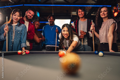 Quadro su tela Diverse group of young friends enjoying a billiard game together in social bar,