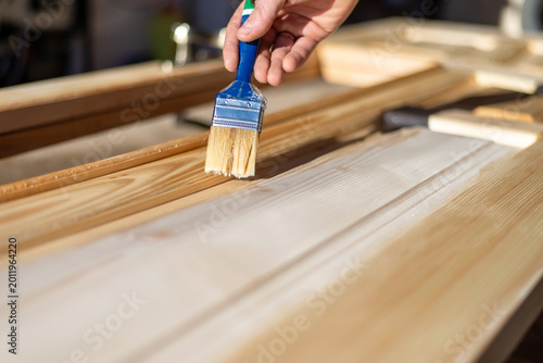 Fotografie Applying wood varnish with brush on new wooden doors
