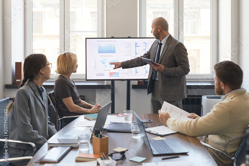 Canvastavla Businessman presenting analytics dashboard to colleagues during office meeting, pointing at screen and discussing strategy
