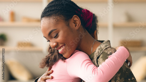 Foto A woman in military uniform hugs a young child in a warm indoor space