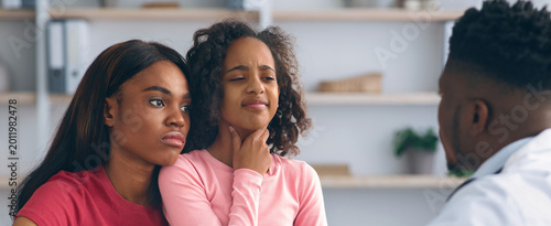 Foto A mother and her daughter are seated in a clinic room talking to a doctor