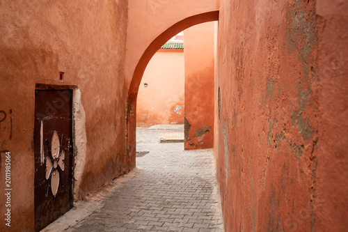 Tableau sur toile Back Alleys of Marrakech Medina: Narrow Orange Passage With Archway and Weathere