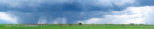 Dark rain cloud with storm over green field with path