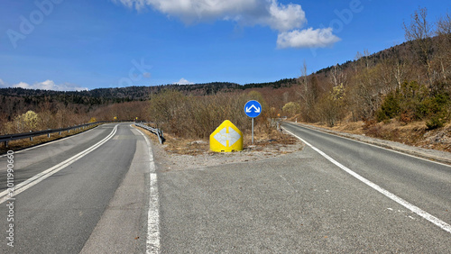 Cuadro en lienzo Highway junction with blue traffic sign and yellow road marker in mountain lands