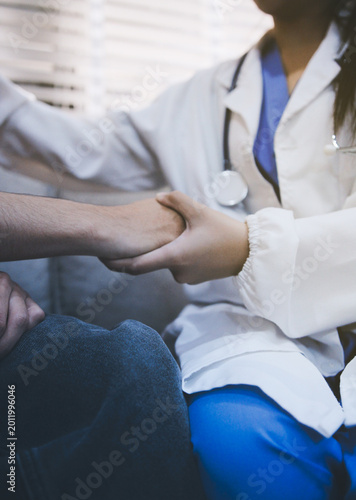 A doctor is holding hands with an elderly patient.