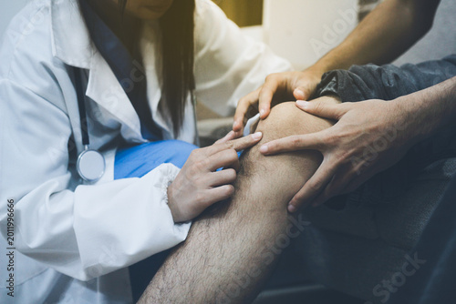 Female doctor examining male patient leg in hospital