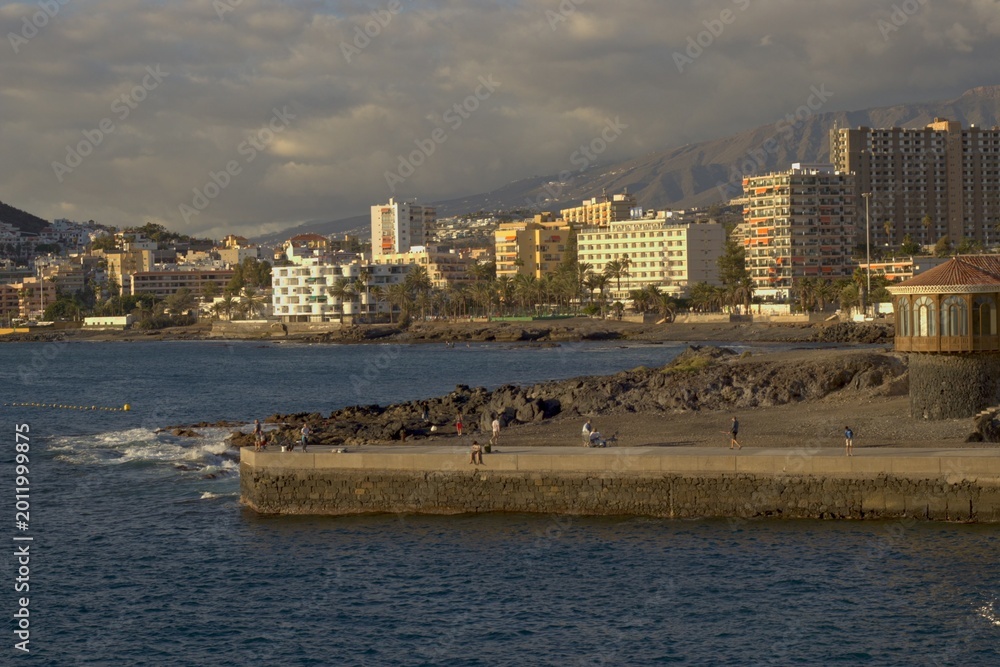 Obraz premium Scenic Coastal City Skyline with Mountains at Sunset in Los Christianos, Tenerife.