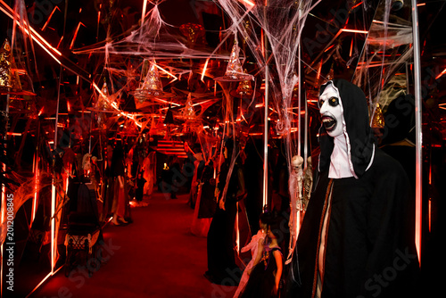 The atmospheric photography from the Halloween-themed event features a dramatic Halloween-inspired set, framed by spooky costumes, faux spider webs and mystical red lighting.