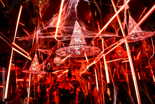The atmospheric photography from the Halloween-themed event features a dramatic Halloween-inspired set, framed by spooky costumes, faux spider webs and mystical red lighting.