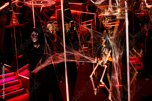 The atmospheric photography from the Halloween-themed event features a dramatic Halloween-inspired set, framed by spooky costumes, faux spider webs and mystical red lighting.