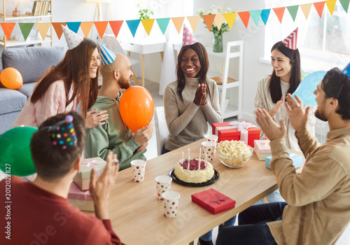 Konstfotografi Group of happy diverse young people gathered around table celebrating birthday together