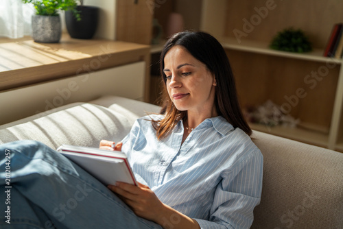Obraz na plátně Young woman writing notes in notebook at home