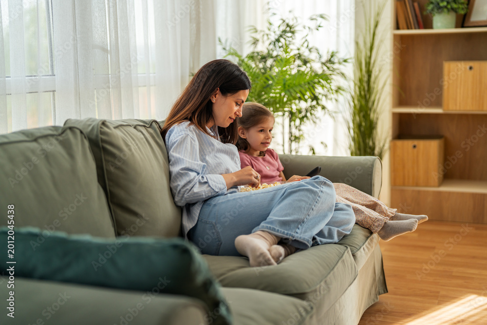 Obraz premium Mother and child relaxing watching television with popcorn