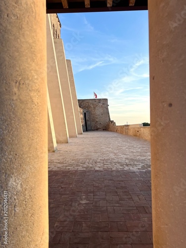 Sunlit stone corridor framed by ancient walls in Ciutadella de Menorca, Mediterranean architecture with warm evening light and minimalist travel aesthetic.