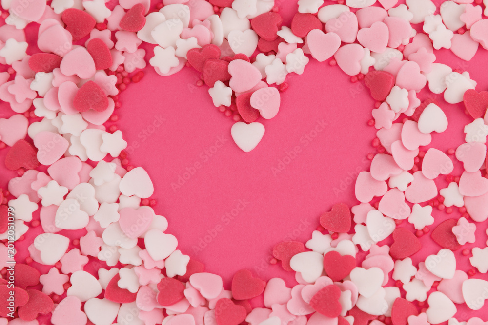 Obraz premium Heart shaped sprinkles forming heart outline on pink