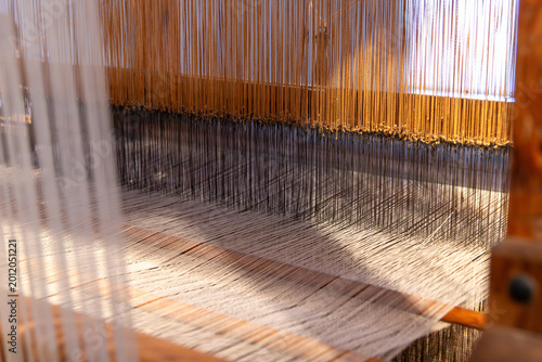 Fotografi Weft and warp interaction forming fabric on wooden loom surface