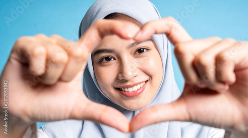 Smiling woman forms a heart shape with her fingers, showing love and affection