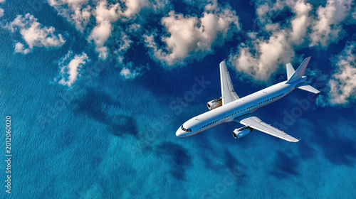 Aerial view of a commercial airplane flying over blue tropical ocean water