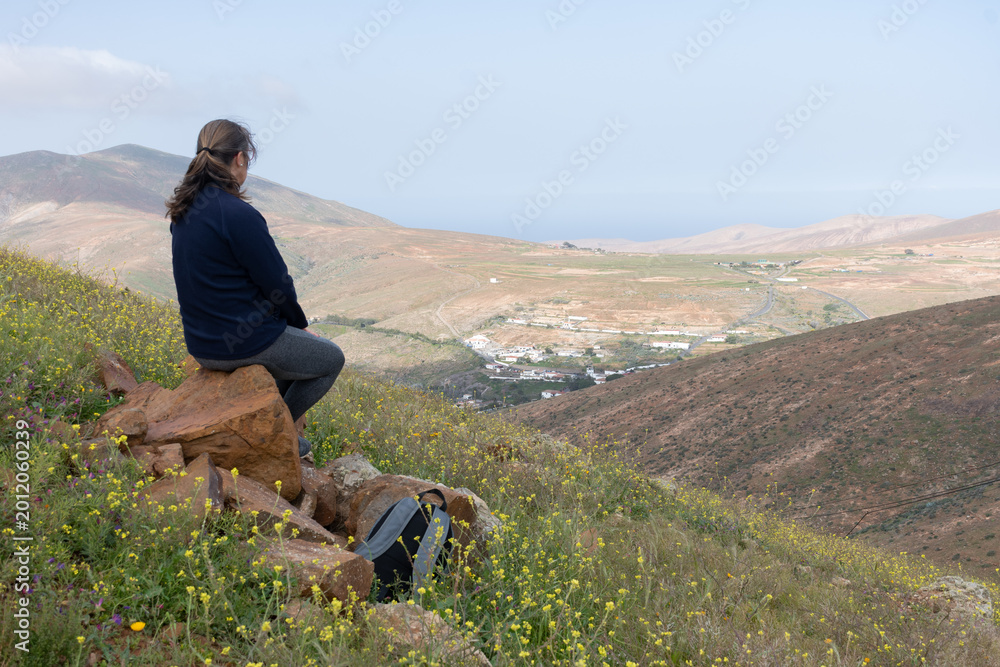 Fototapeta premium Sentada en una roca contemplando el pueblo a lo lejos