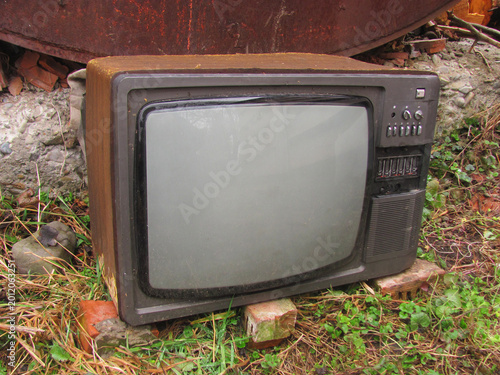 An abandoned vintage CRT television placed on bricks outside, ready for electronic waste recycling