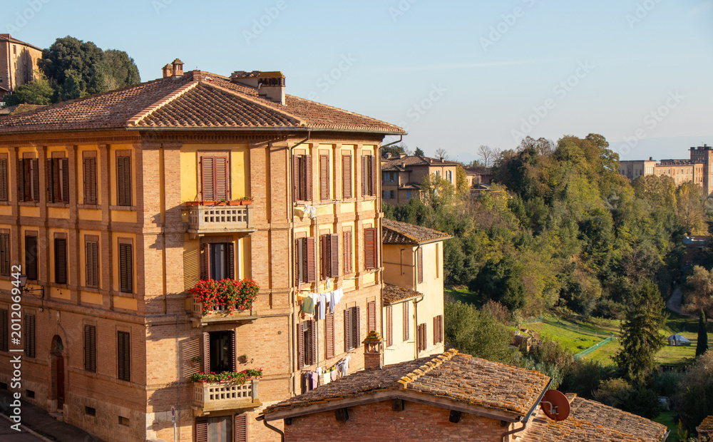 Obraz premium Corner Building with Flower Balconies in Siena Tuscany During Golden Hour with Traditional Italian Urban Architecture