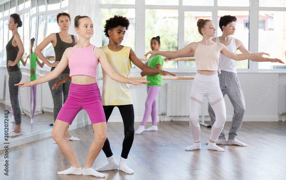 Obraz premium Slim teen boy and girl doing together plie position of ballet during choreography classes