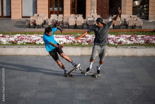 Bilde på lerret Skaters performing balancing tricks on skateboards in urban square