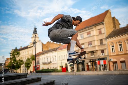 Photos Skateboarder performing an ollie trick in city square