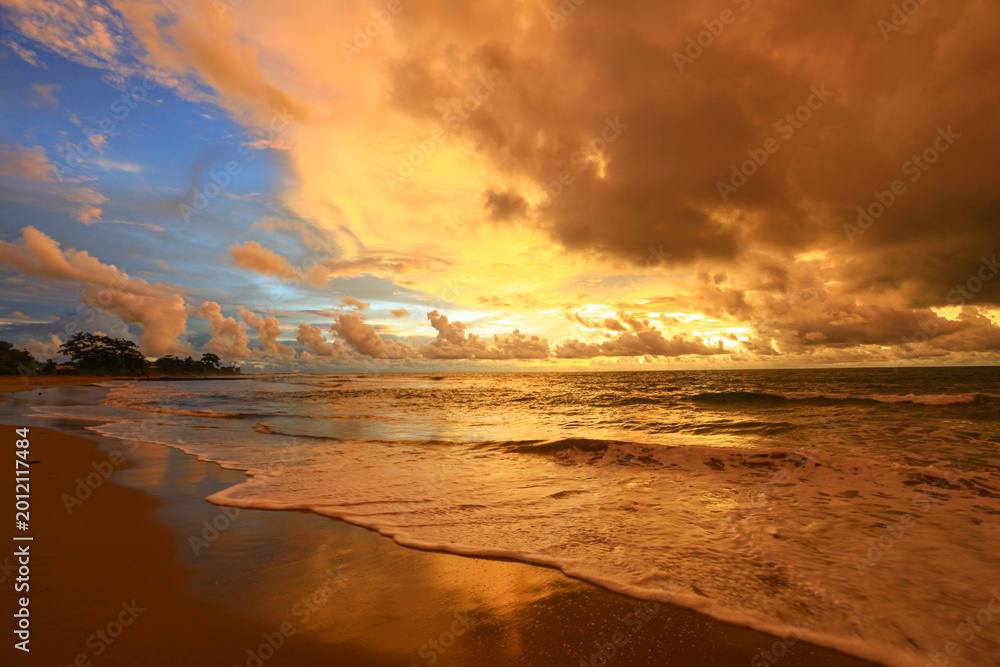 Obraz premium Golden sunset paints sky and sea in warm hues. Silent beach invites calm, reflection, and peace.
