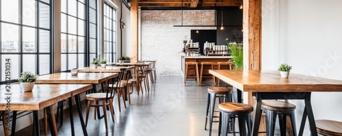 Sunlit modern industrial cafe interior with long wooden tables, black-framed windows, white brick wall and potted plants. A clean, inviting space for dining or work. Cafe, Interior
